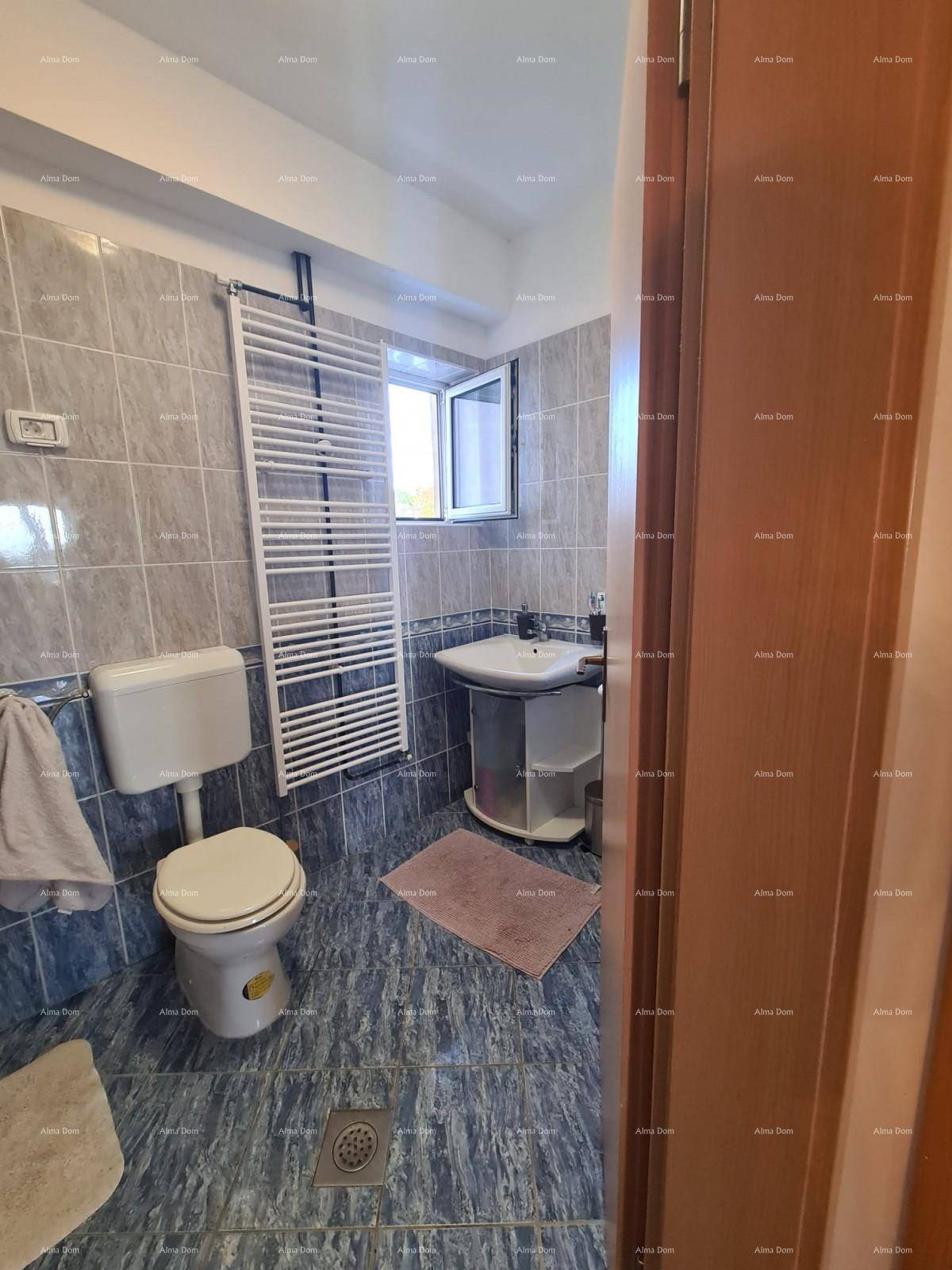 Badezimmer mit WC, Waschbecken und beheiztem Handtuchhalter, komplett gefliest.