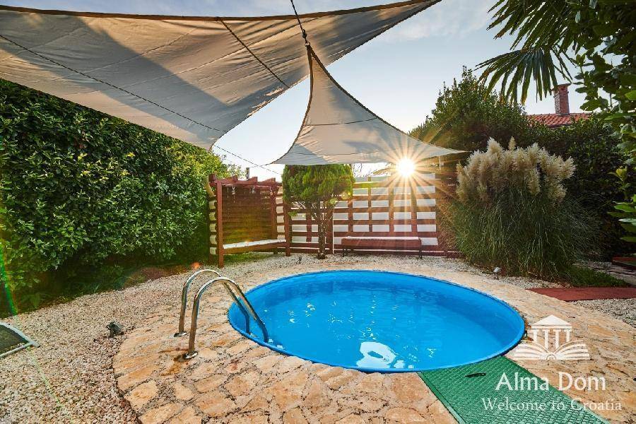 Kleiner runder Pool mit Sonnensegeln, umgeben von Kies und Steinpflaster im Garten.