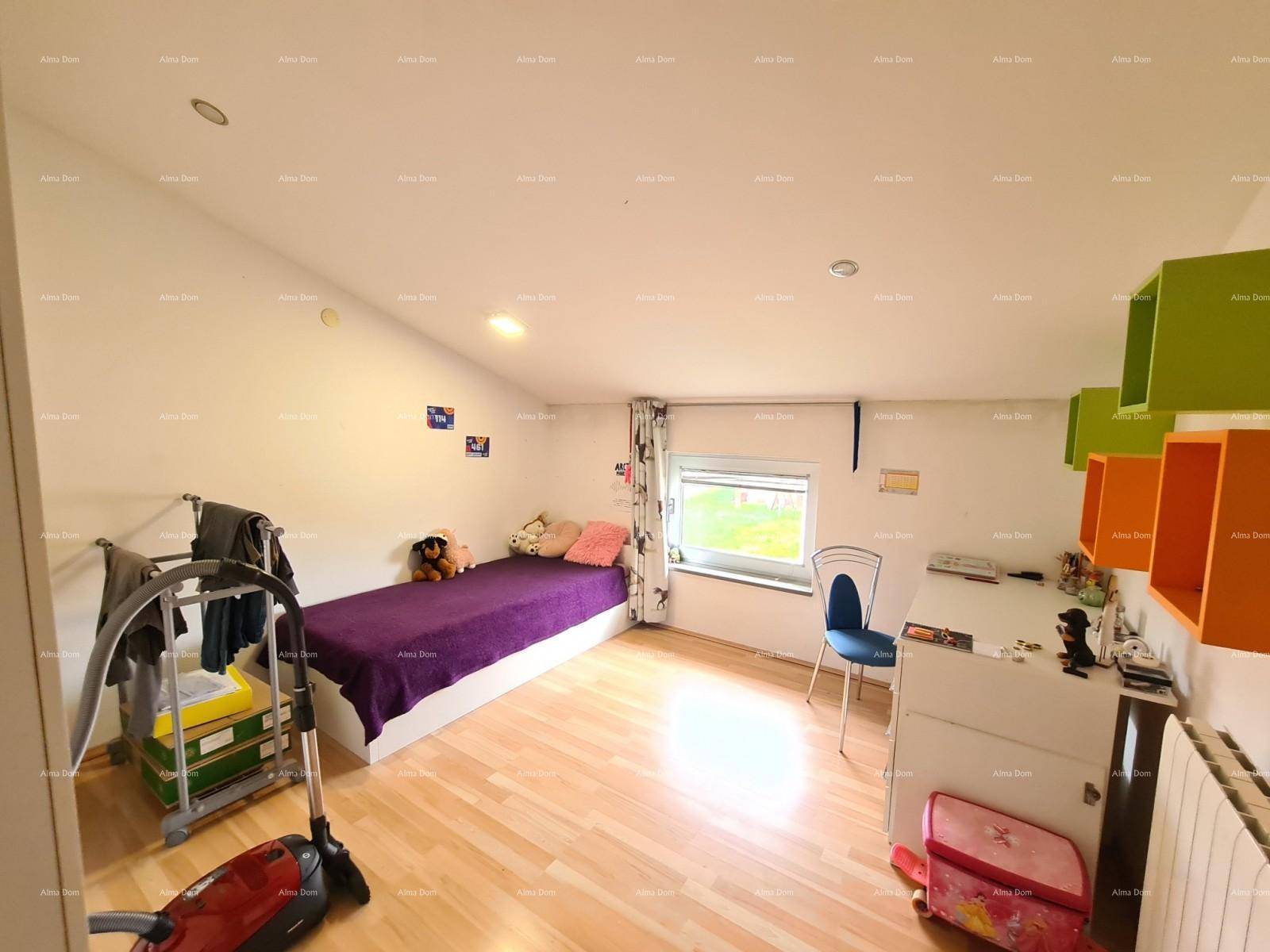 Kinderzimmer im Dachgeschoss mit Holzboden, kleinem Fenster und bunten Regalen.