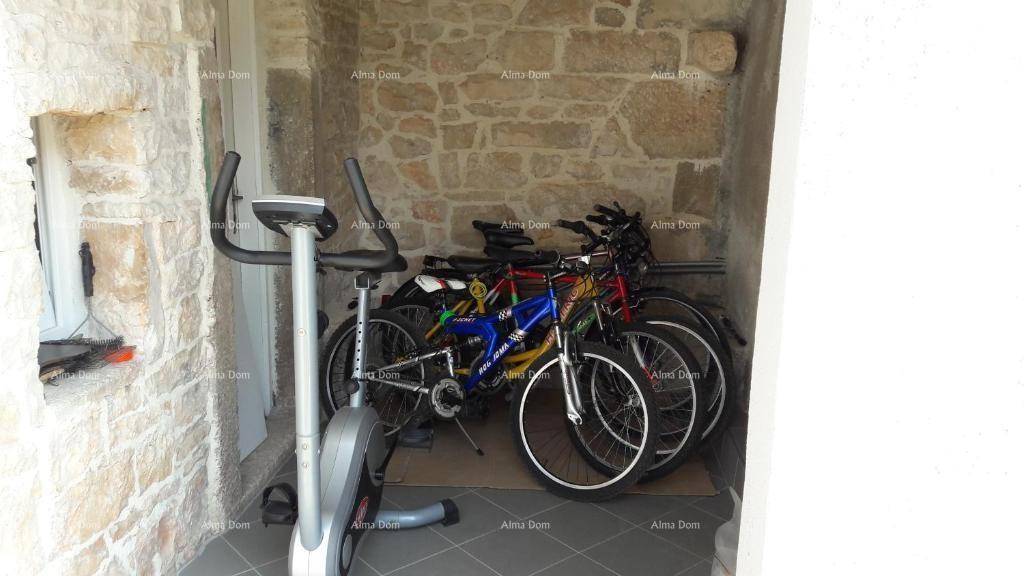 Überdachter Außenbereich mit Fitnessrad und mehreren Fahrrädern zur Aufbewahrung.