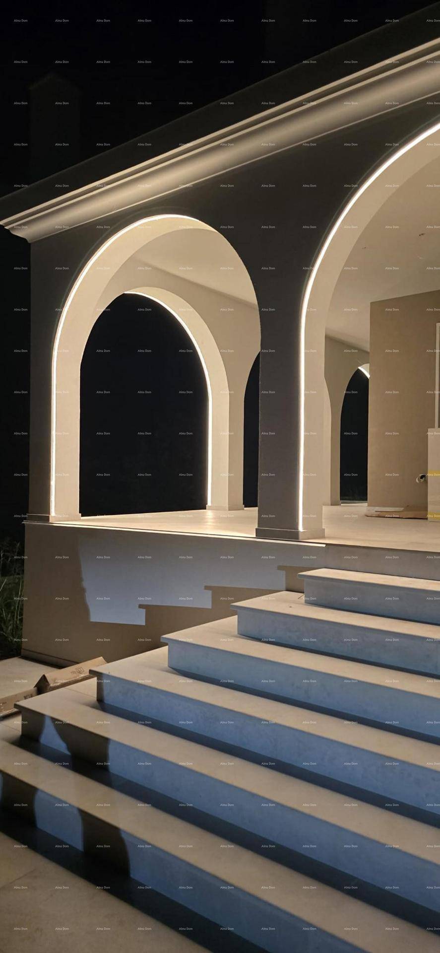 Beleuchtete Arkaden und Treppen der Villa bei Nacht, mit stimmungsvoller Akzentbeleuchtung.