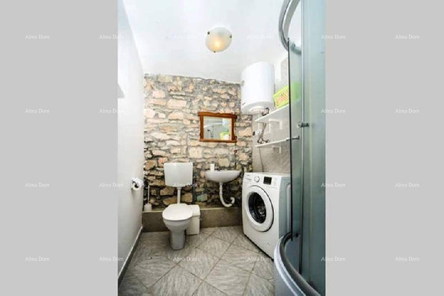 Kompaktes Badezimmer mit Dusche, WC, Waschbecken und Waschmaschine, akzentuiert durch eine Steinwand.