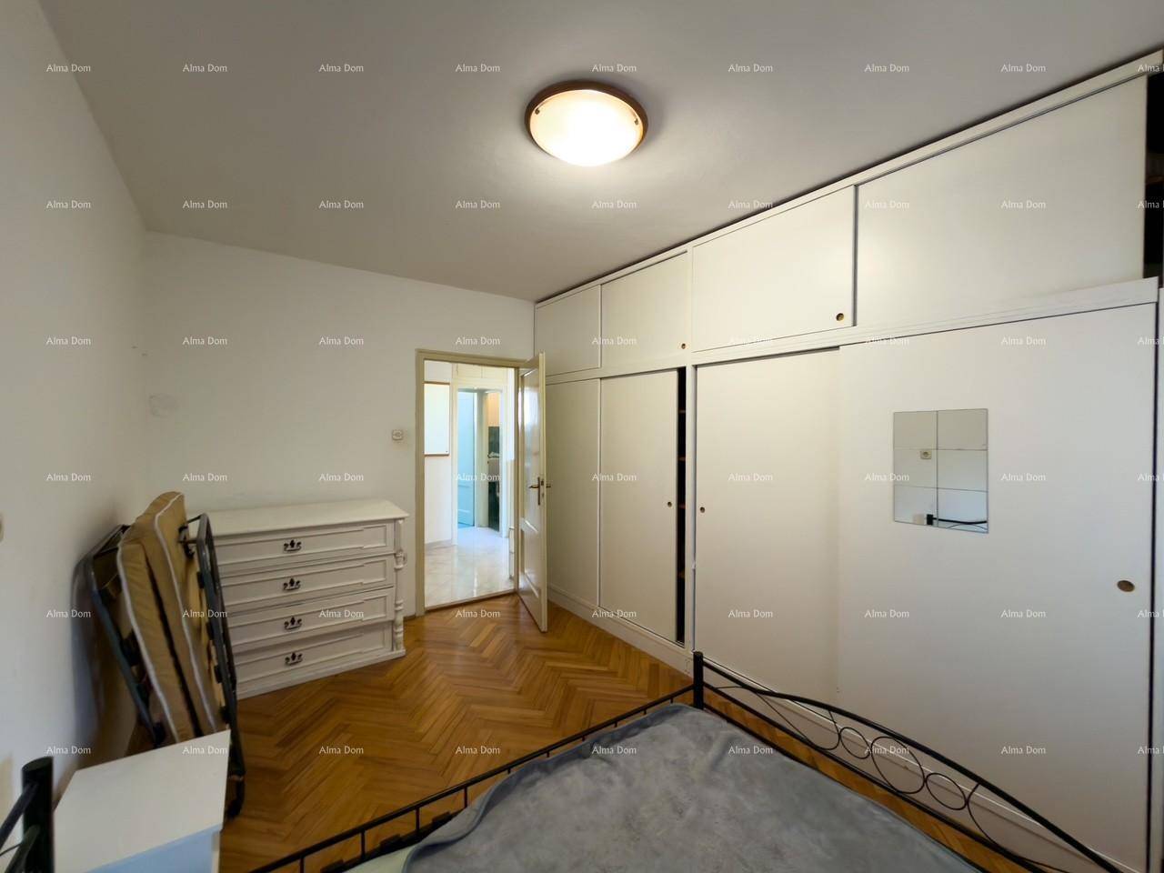 Schlafzimmer mit Holzfußboden, Bett und einem Schrank, der zum Flur führt.