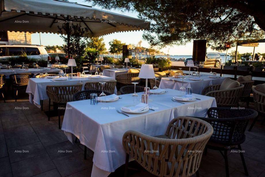 Elegante Außenterrasse eines Restaurants mit gedeckten Tischen und Blick auf das Meer bei Sonnenuntergang.