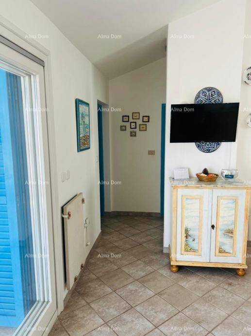 Heller Flur mit dekorativem Schrank, Wandfernseher und Zugang zu einem Außenbereich.