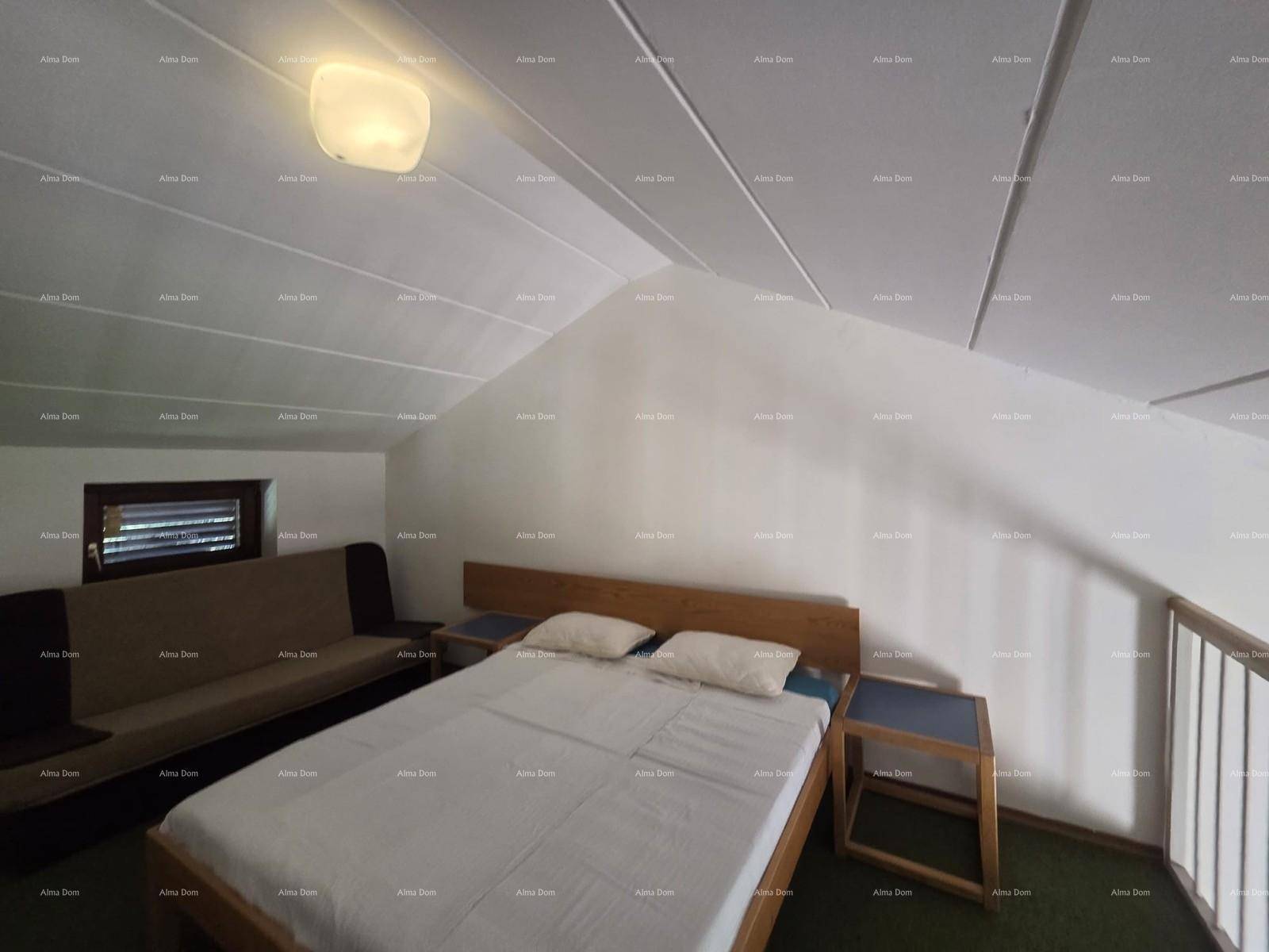 Gemütlicher Schlafbereich auf der Empore mit Doppelbett, Sofa und Fenster unter der Dachschräge.