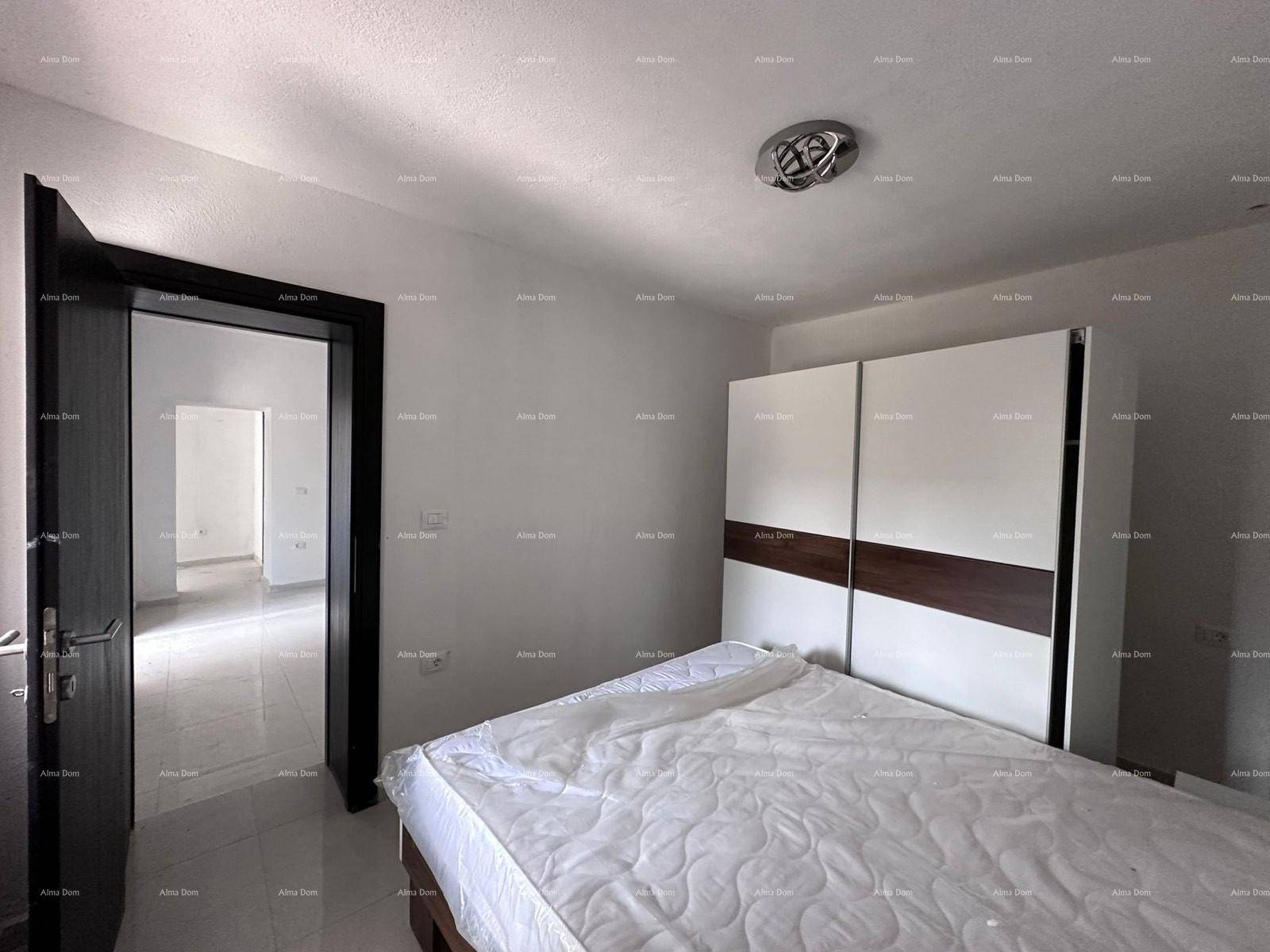 Schlafzimmer mit Bett und Kleiderschrank, Blick durch die offene Tür in einen weiteren Raum.