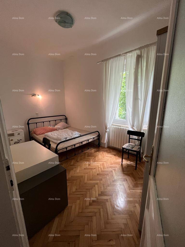 Schlafzimmer mit Metallbett, Holzboden und Fenster mit Blick ins Grüne, das Ruhe verspricht.