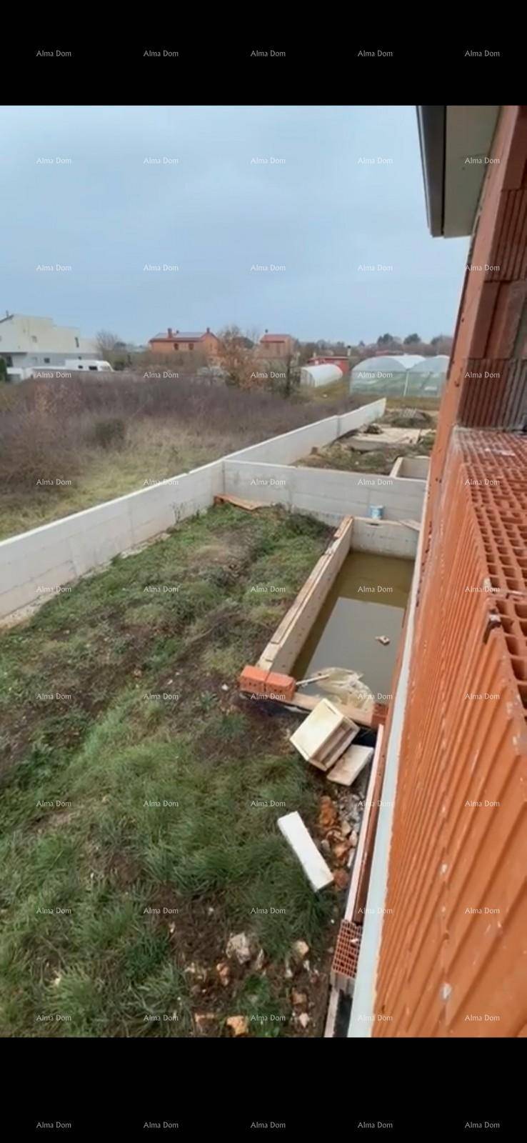 Blick von oben auf die Baustelle mit Betonmauer und wassergefülltem Graben.