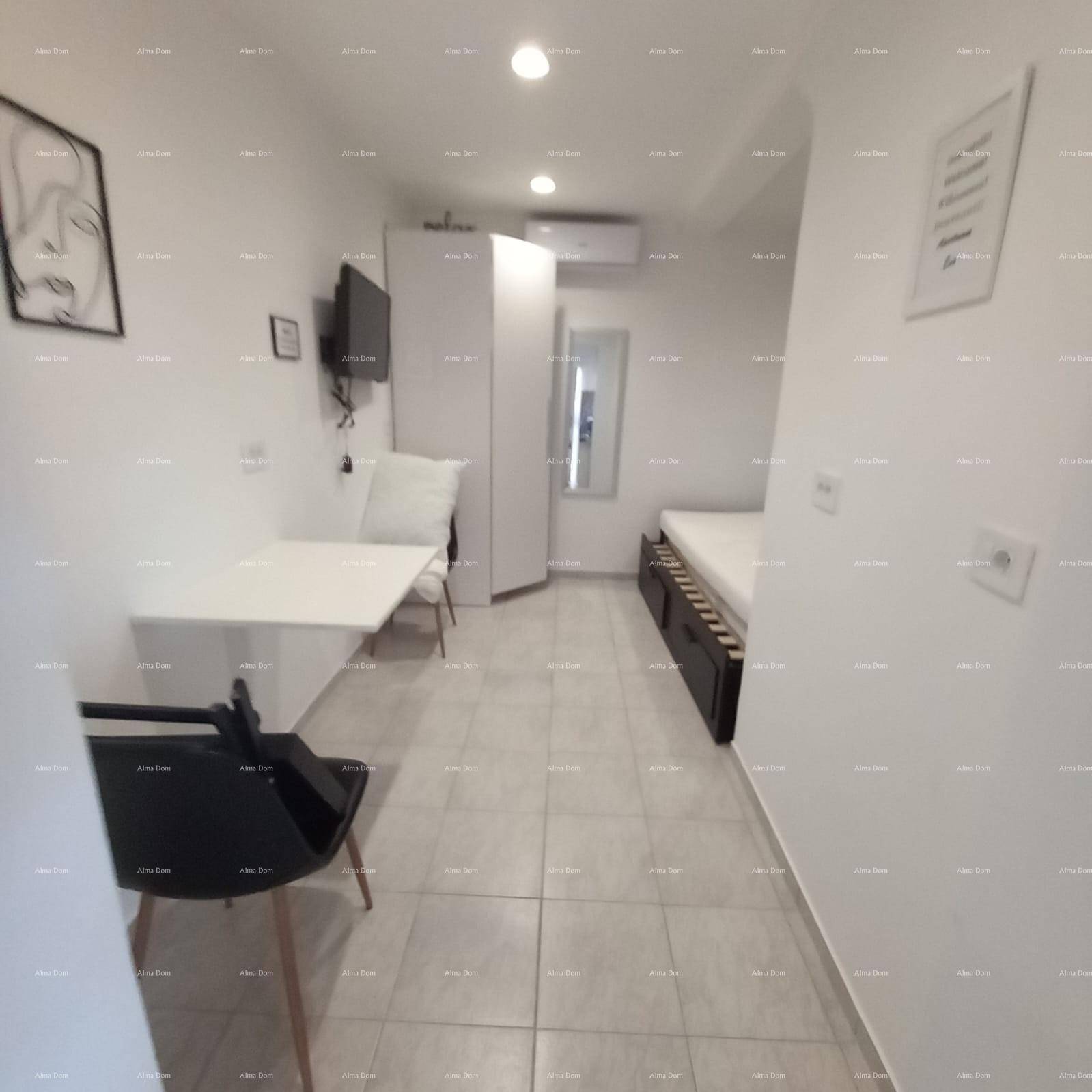 Kompakter Wohnbereich mit Schlafgelegenheit, Esstisch und Schrank, hell gefliest.
