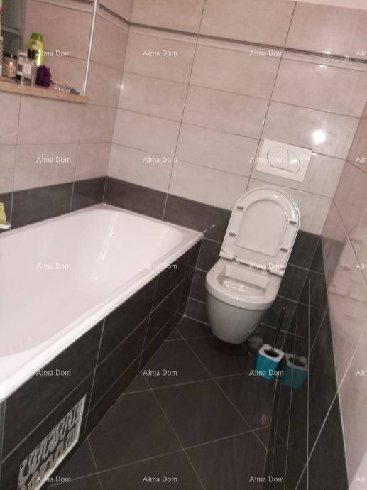 Badezimmer mit Badewanne, wandhängendem WC und dunklen Bodenfliesen.