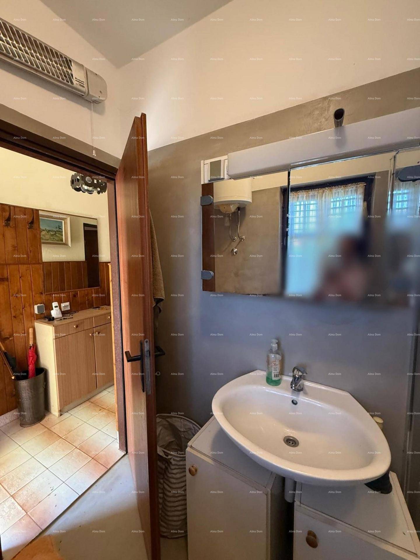 Badezimmer mit Waschbecken, Spiegelschrank und Blick in einen angrenzenden Raum.