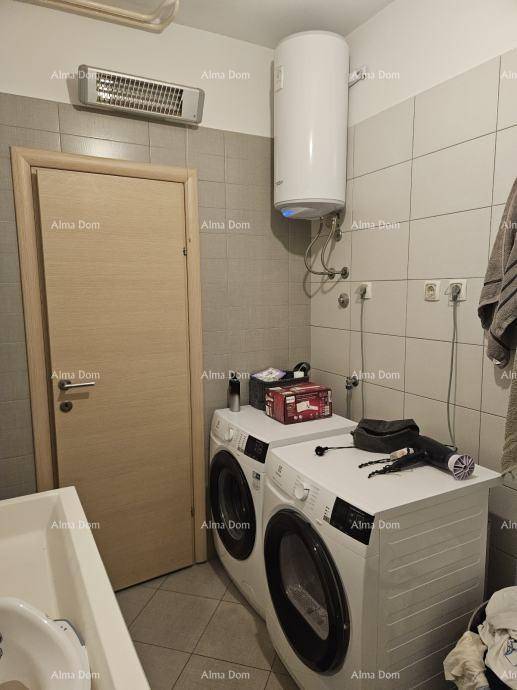 Badezimmer mit Waschmaschine, Trockner und Warmwasserboiler, gefliesten Wänden und Boden.