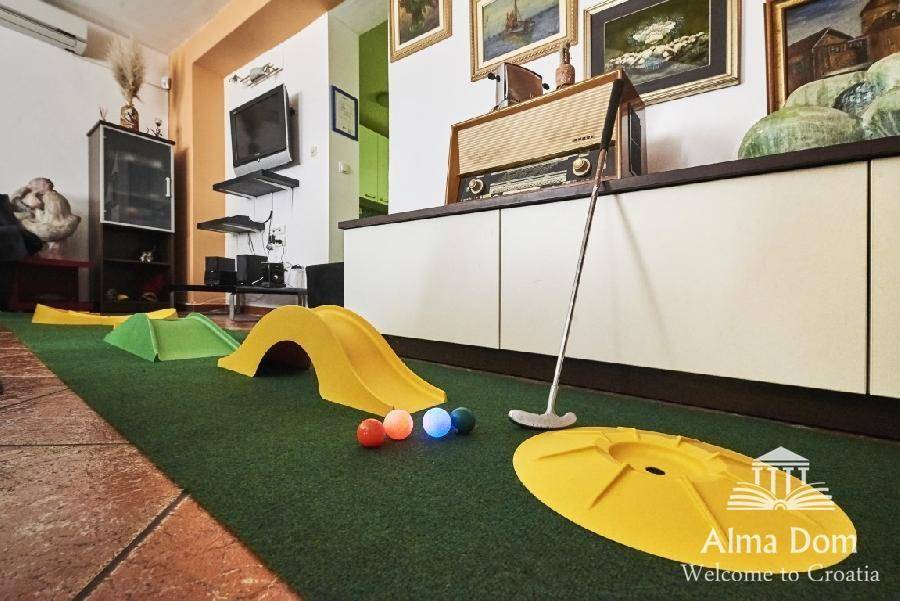 Innenbereich mit Minigolfanlage, einem Vintage-Radio und Fernseher im Hintergrund.