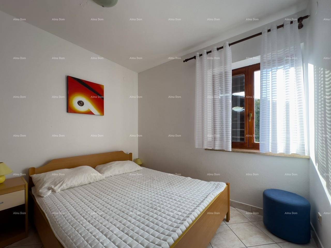 Schlafzimmer mit Doppelbett, Holznachttischen und einem Fenster mit weißen Vorhängen, Fliesenboden.