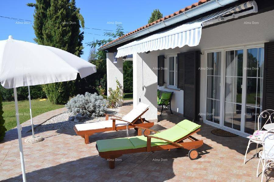 Gemütliche Terrasse mit Sonnenliegen, Sonnenschirm und Markise vor dem Haus an einem sonnigen Tag.