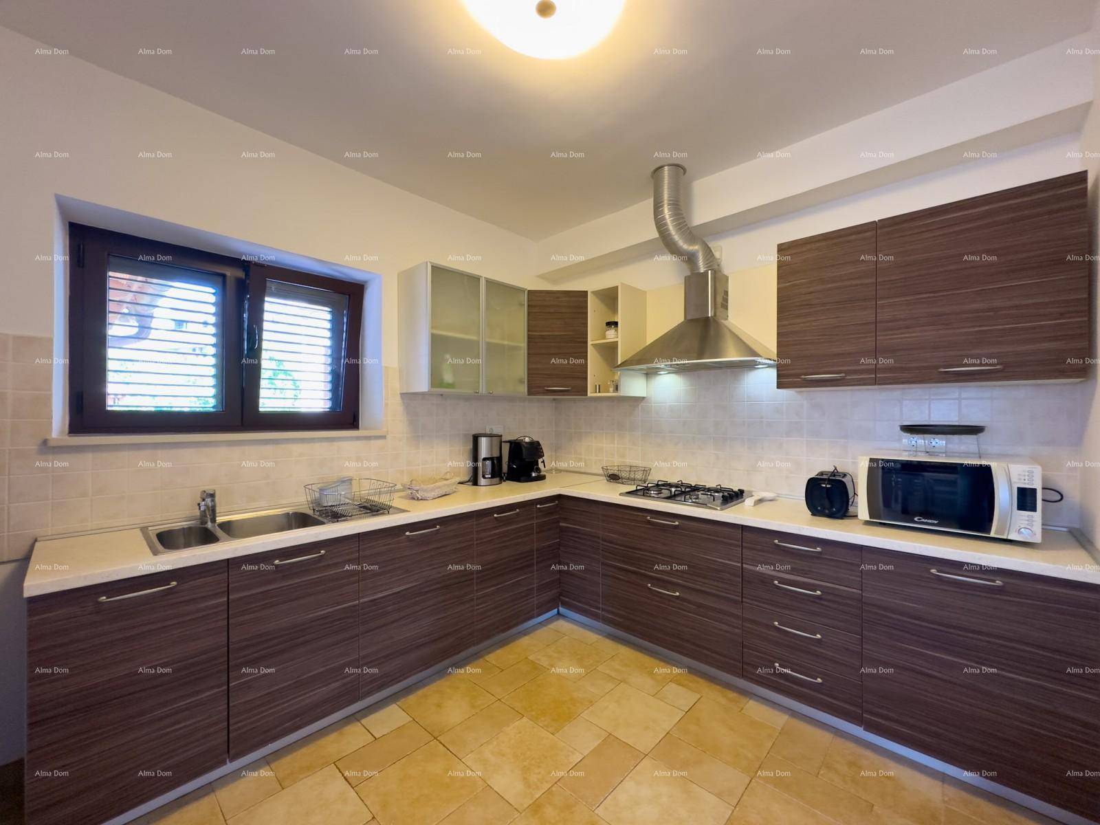 Moderne Küche mit dunklen Holzfronten, hellen Arbeitsplatten, Gasherd und Fenster.