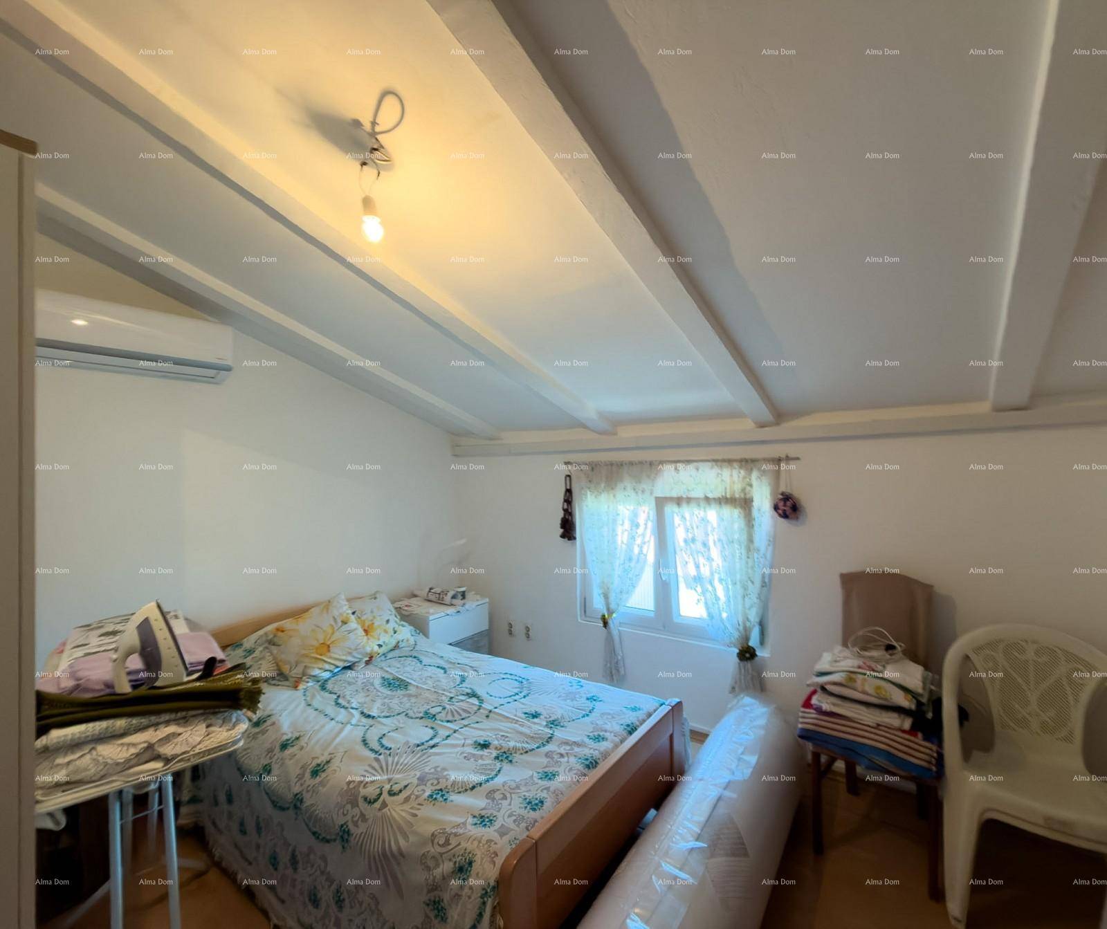 Schlafzimmer mit Holzbalkendecke, Einzelbett und Fenster, das für natürliche Belichtung sorgt.