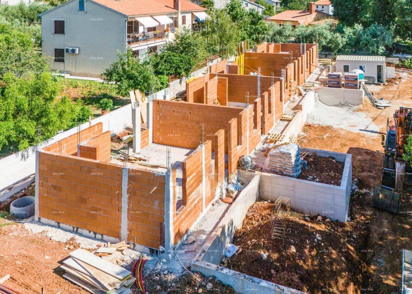 Luftaufnahme einer Baustelle mit im Bau befindlichen Reihenhäusern aus Ziegelmauerwerk.