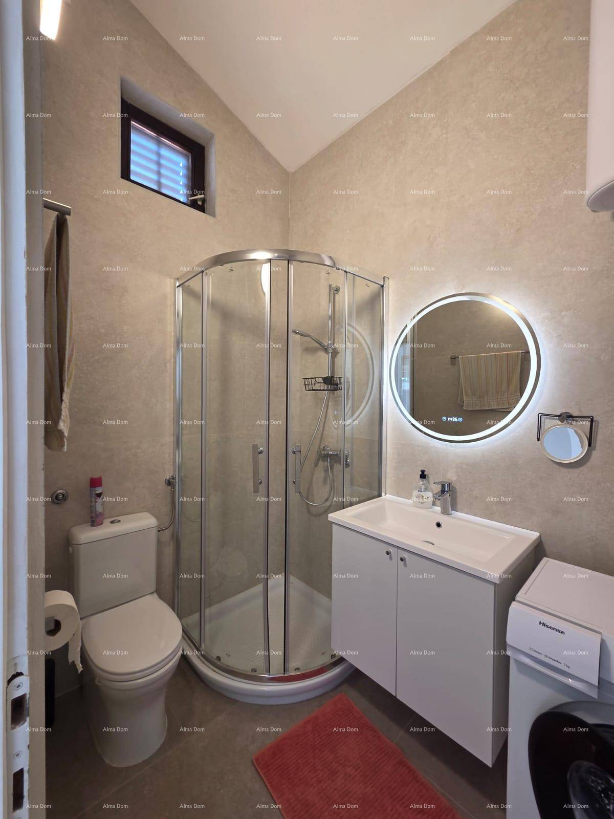 Modernes Badezimmer mit Duschkabine, WC, Waschbecken und beleuchtetem Spiegel, funktional eingerichtet.