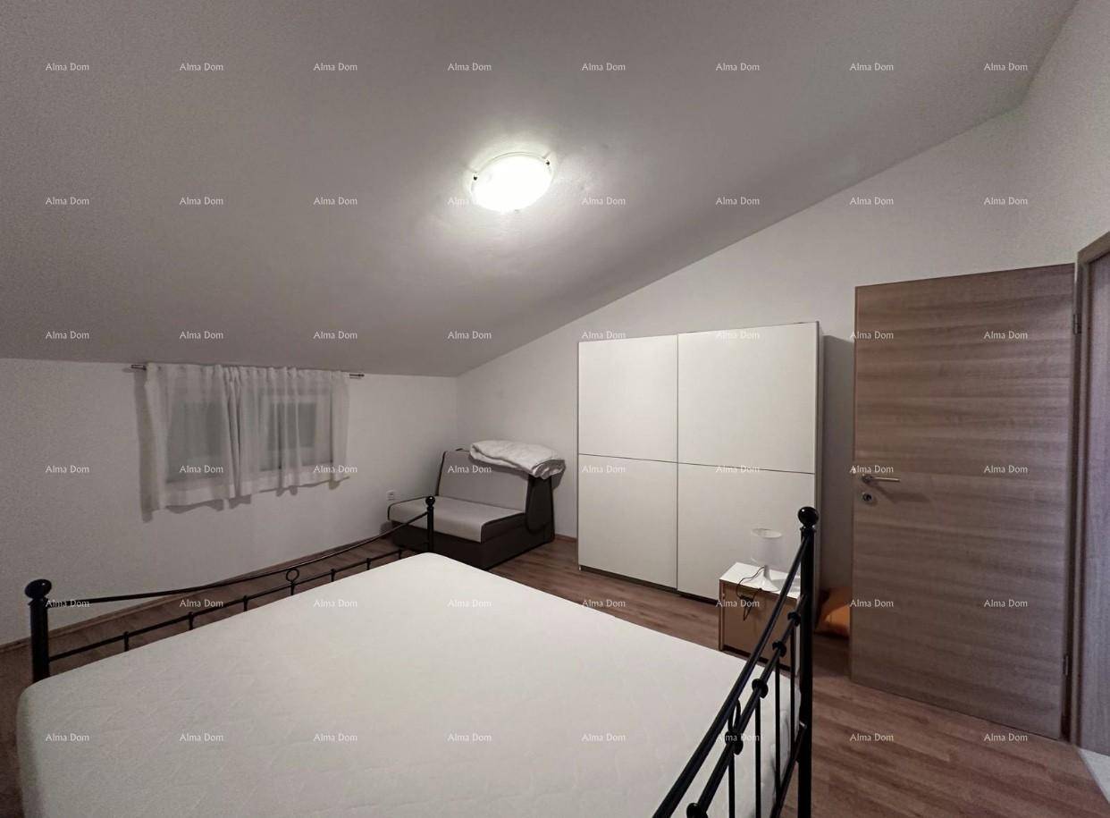 Schlafzimmer im Dachgeschoss mit Metallbett, Kleiderschrank und schrägen Wänden.