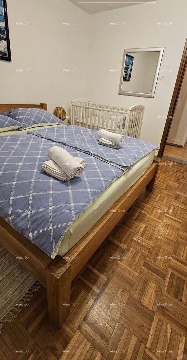 Schlafzimmer mit Doppelbett, Holzboden und Babybett im Hintergrund.