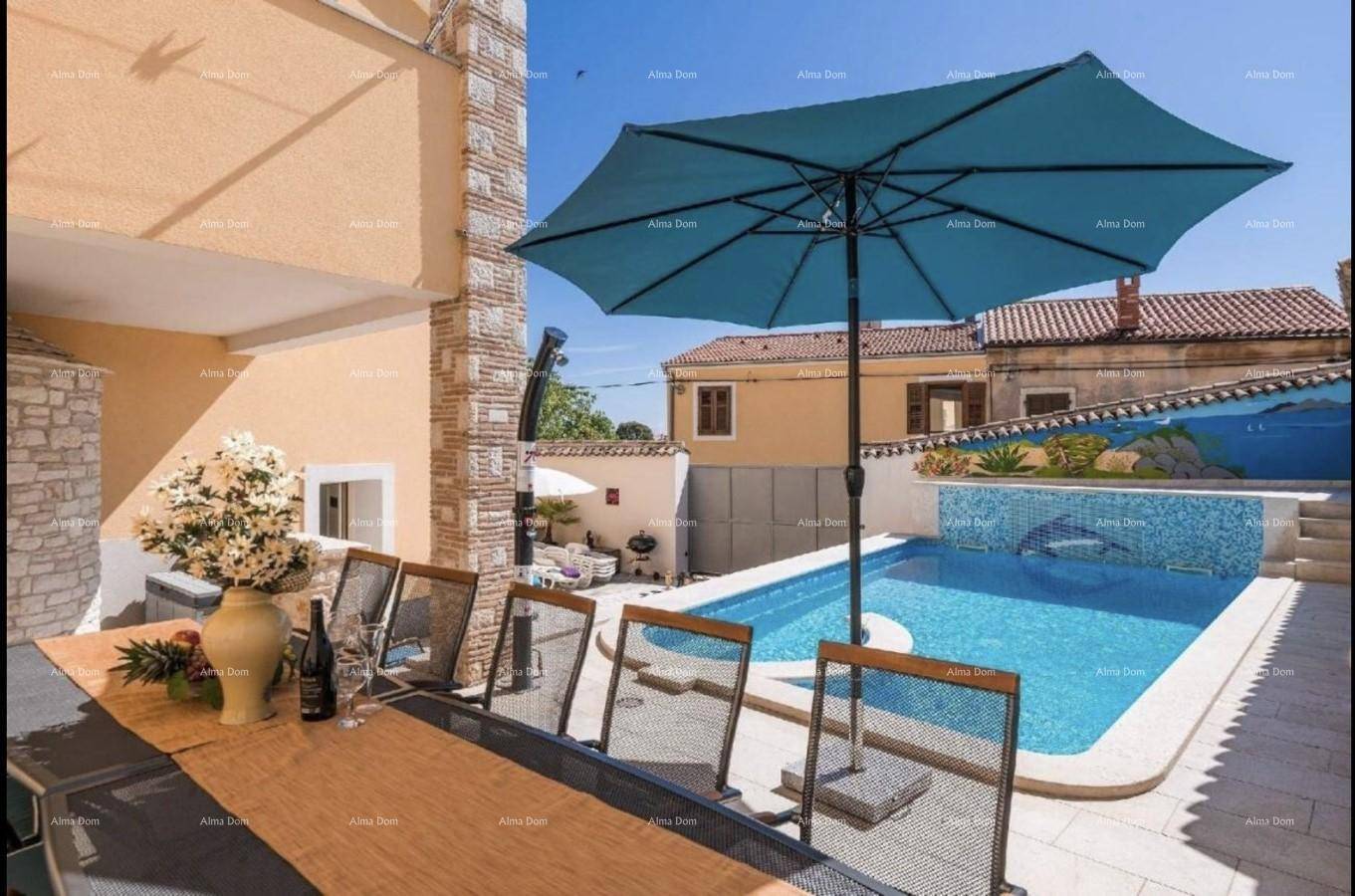Essbereich im Freien mit Blick auf den Pool und einen großen Sonnenschirm.