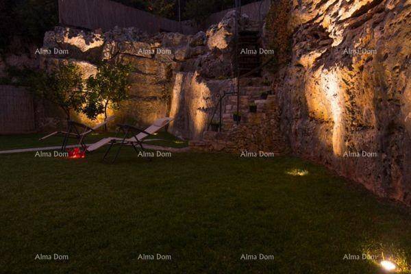 Beleuchteter Gartenbereich bei Nacht mit Felswand und gemütlichen Sitzgelegenheiten.