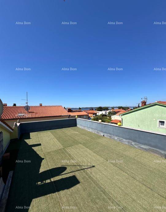 Große Dachterrasse mit Kunstrasen und weitem Blick über die Dächer bis zum Meer.
