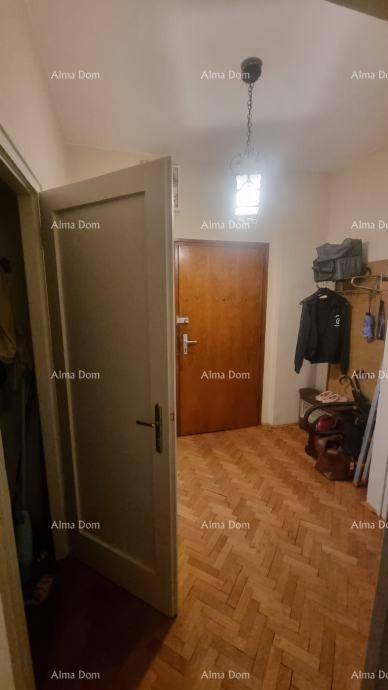Eingangsbereich mit Parkettboden, einer Holztür und einer Garderobe für Mäntel und Taschen.