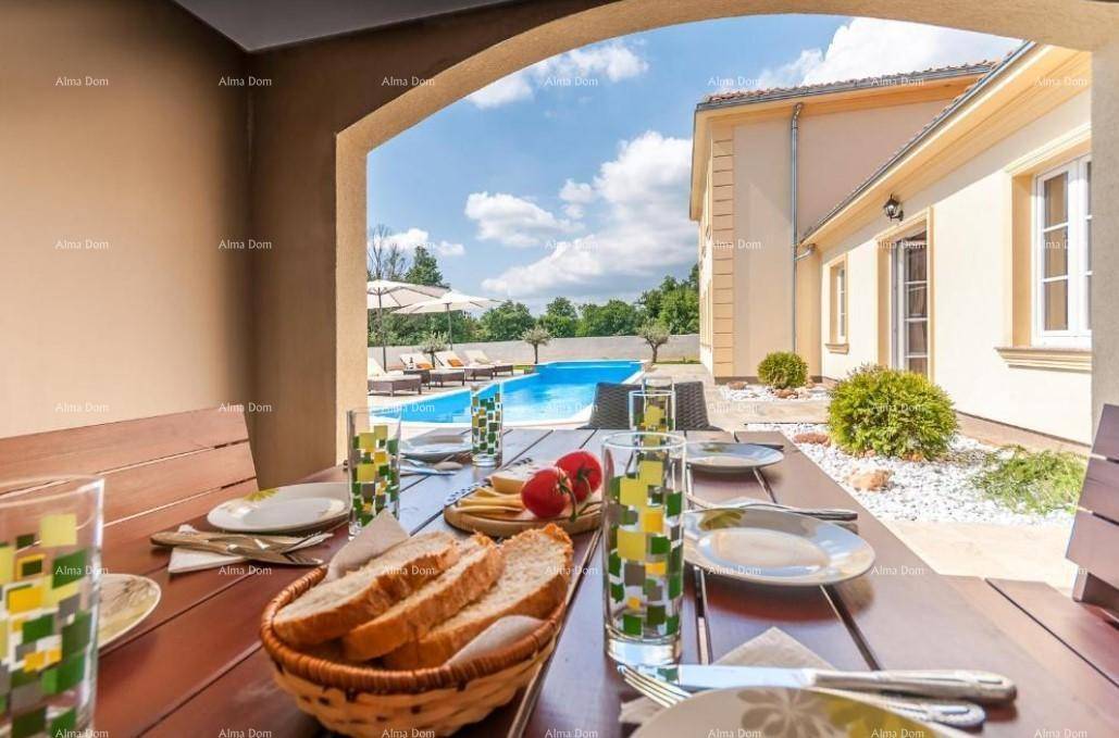 Überdachter Essbereich im Freien mit Holztisch, Blick auf den Pool und die umliegende Landschaft.