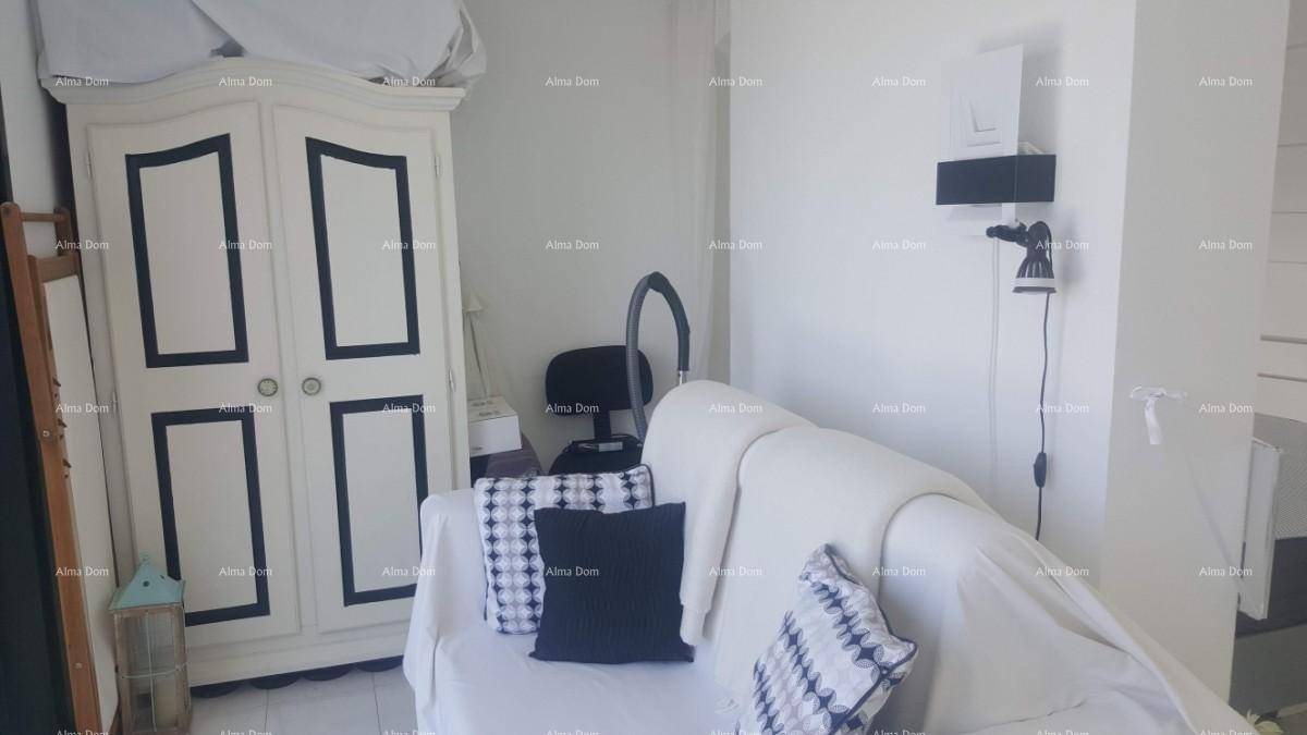 Kleiner Wohnbereich mit weißem Sofa, dekorativem Schrank und einem Spiegel.