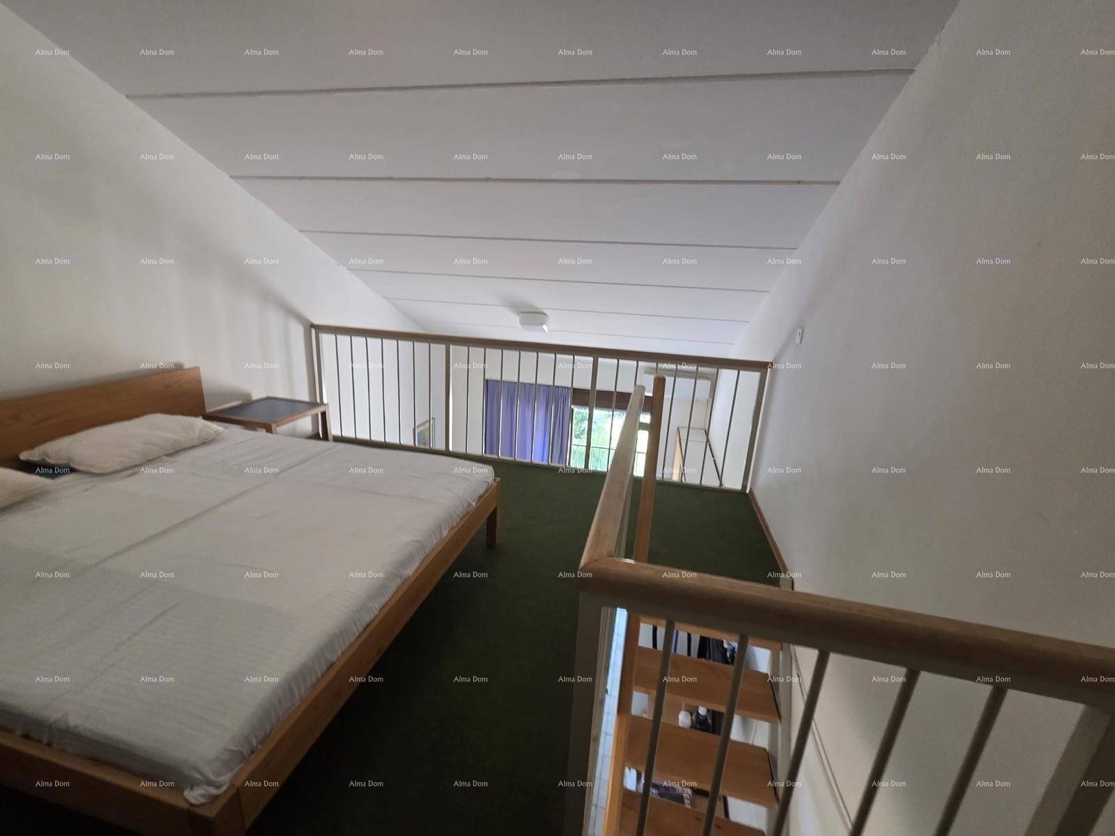 Schlafbereich auf der Empore mit Doppelbett, grünem Teppichboden und Dachschrägen.