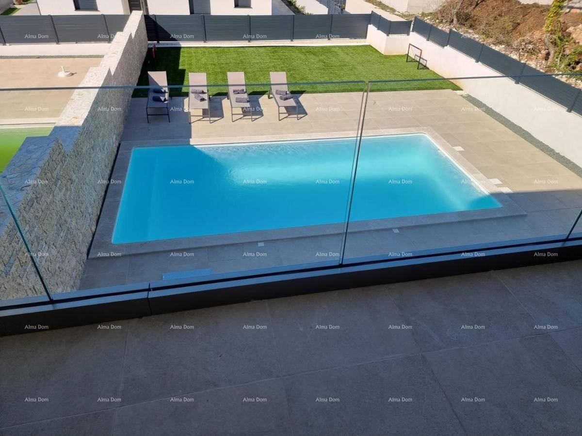 Vogelperspektive des Pools und des Gartens mit Liegestühlen und einem eleganten Glaszaun.