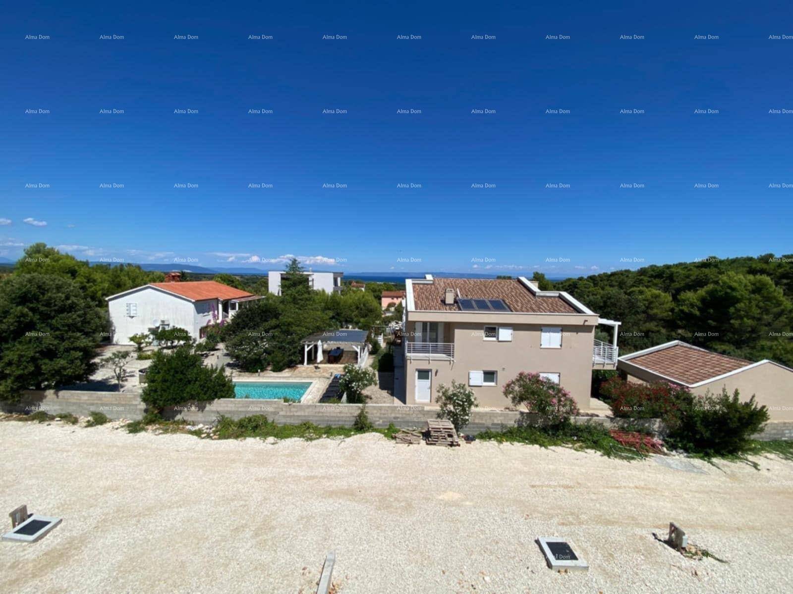 Panoramablick auf Wohnhäuser, einen Swimmingpool und das Meer unter blauem Himmel.