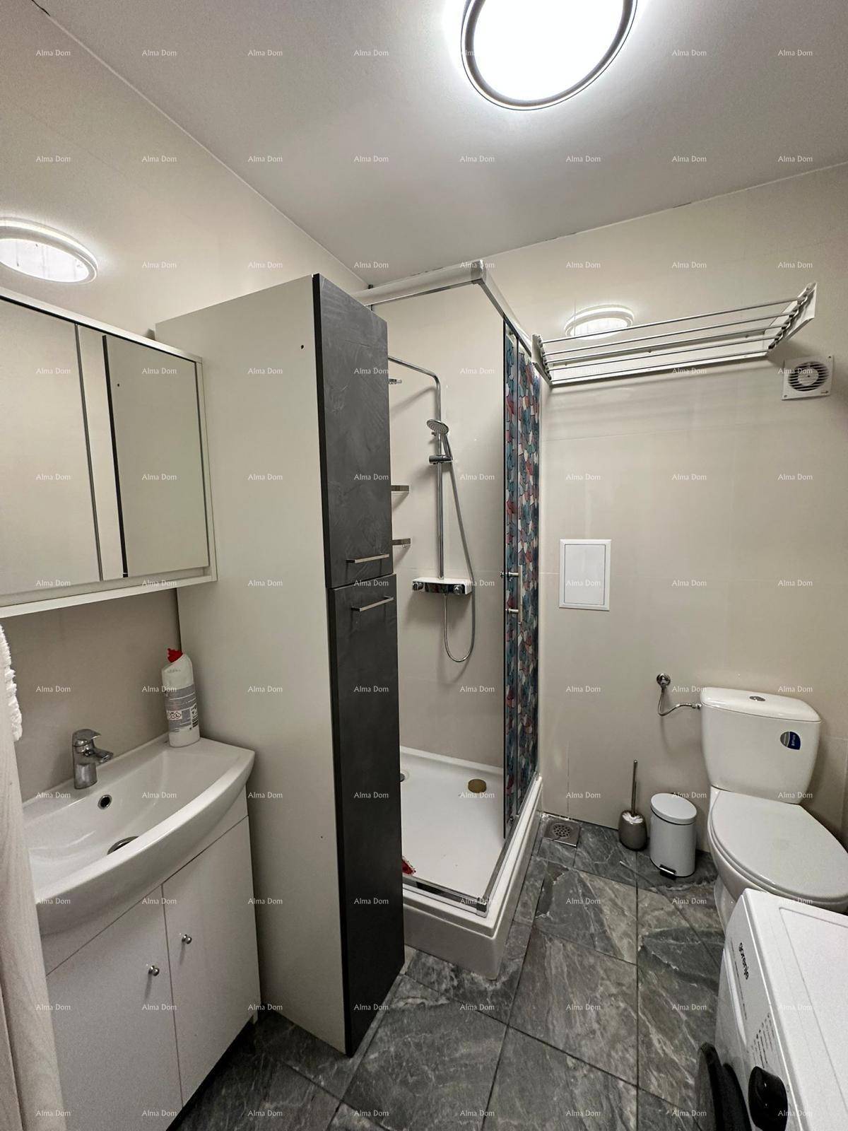 Badezimmer mit Duschkabine, Toilette, Waschmaschine und Warmwasserbereiter für Komfort.