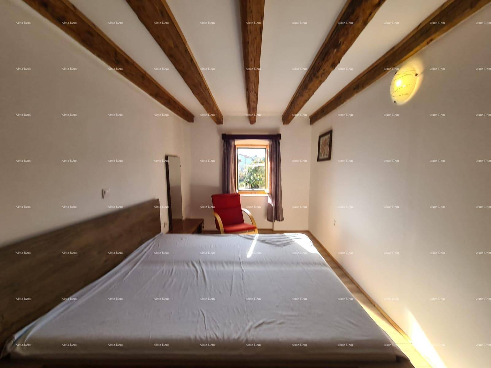 Helles Schlafzimmer mit Holzbalkendecke, großem Bett und einem Fenster, das viel natürliches Licht spendet.