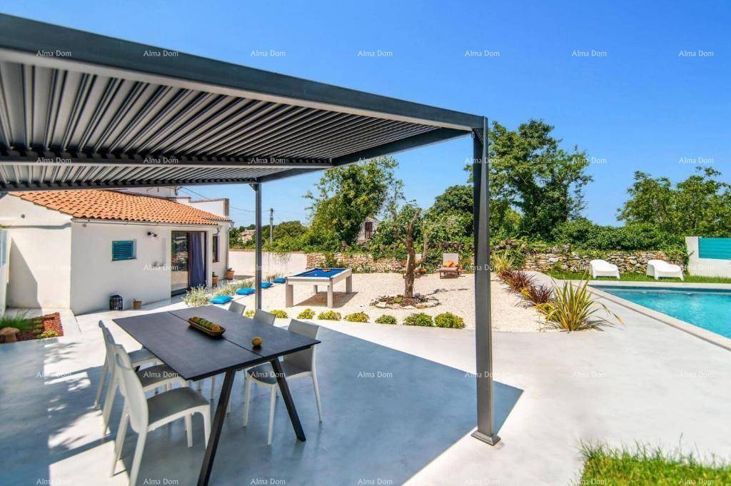 Geräumige Terrasse mit Pergola und Esstisch, umgeben von einem gepflegten Garten und Poolbereich.