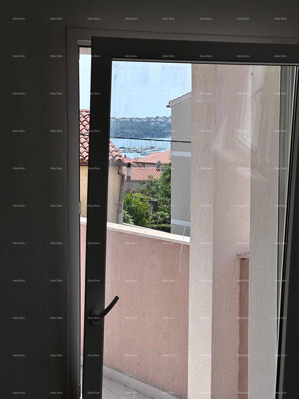 Blick aus einem Fenster auf die roten Dächer und das Meer in der Ferne.
