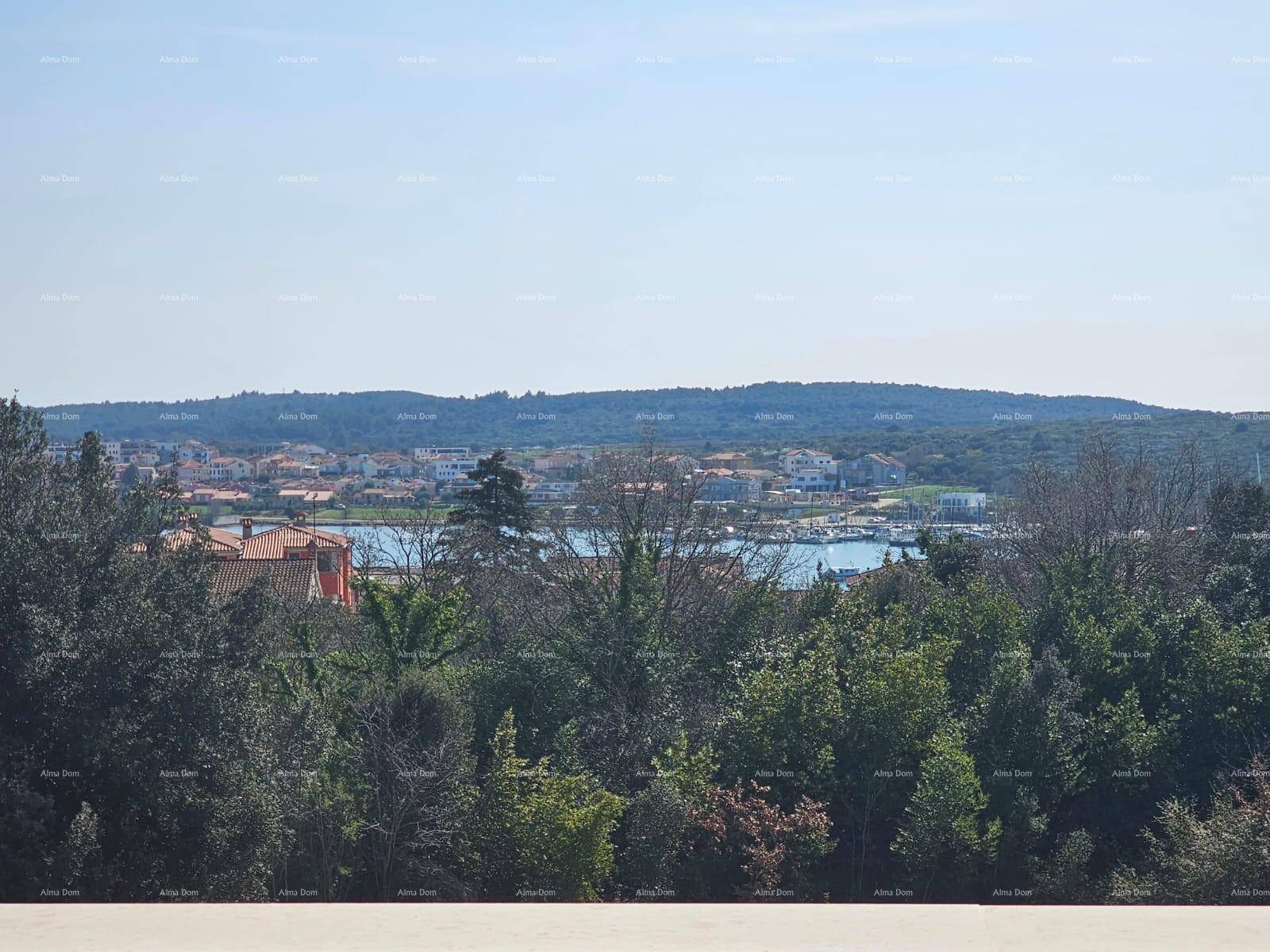 Weitläufiger Blick über eine Küstenstadt mit Hafen und grüner Landschaft.