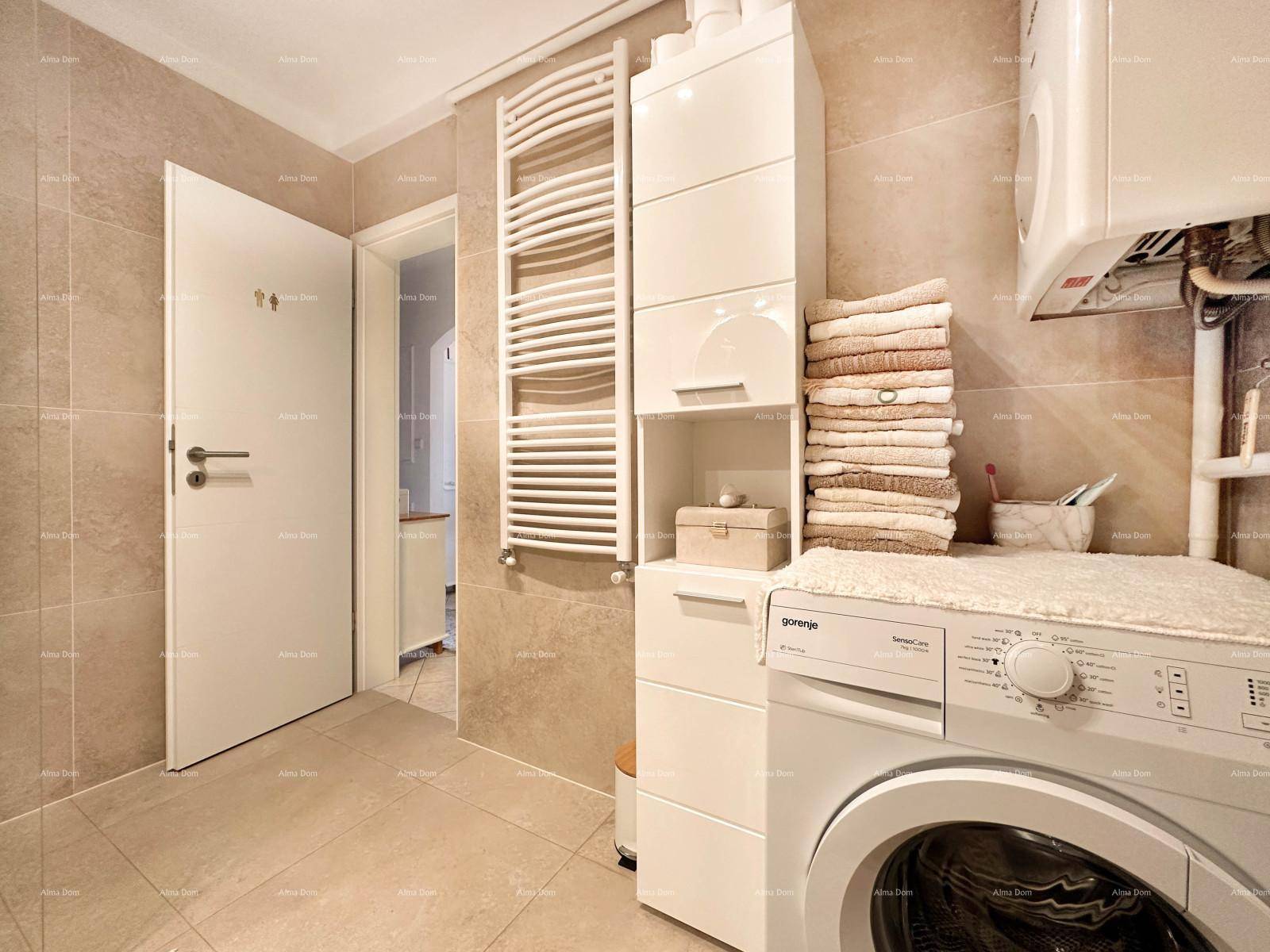 Badezimmer mit Waschmaschine, beheiztem Handtuchhalter und Zugang zu einem weiteren Raum.