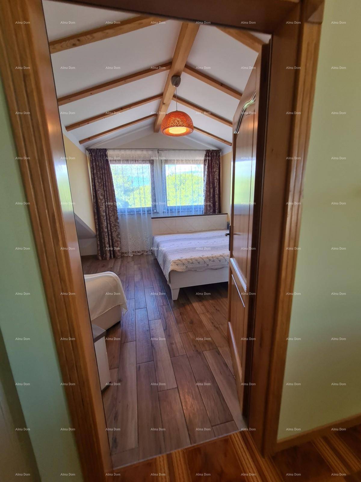 Gemütliches Schlafzimmer mit Holzbalken, schrägen Decken und Holzboden, durch eine Holztür sichtbar.