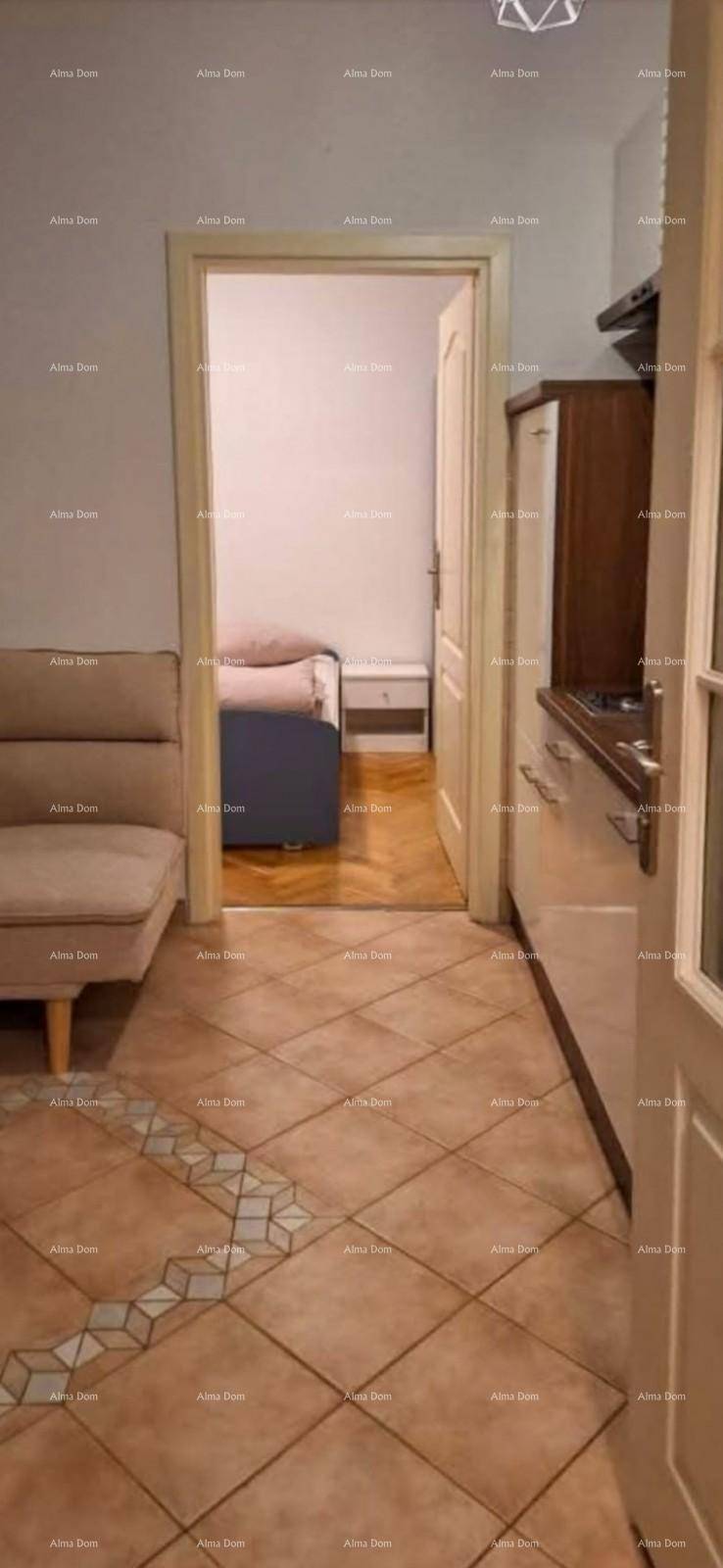 Blick von einem gefliesten Bereich mit Sofa und Küchenzeile in ein angrenzendes Schlafzimmer.