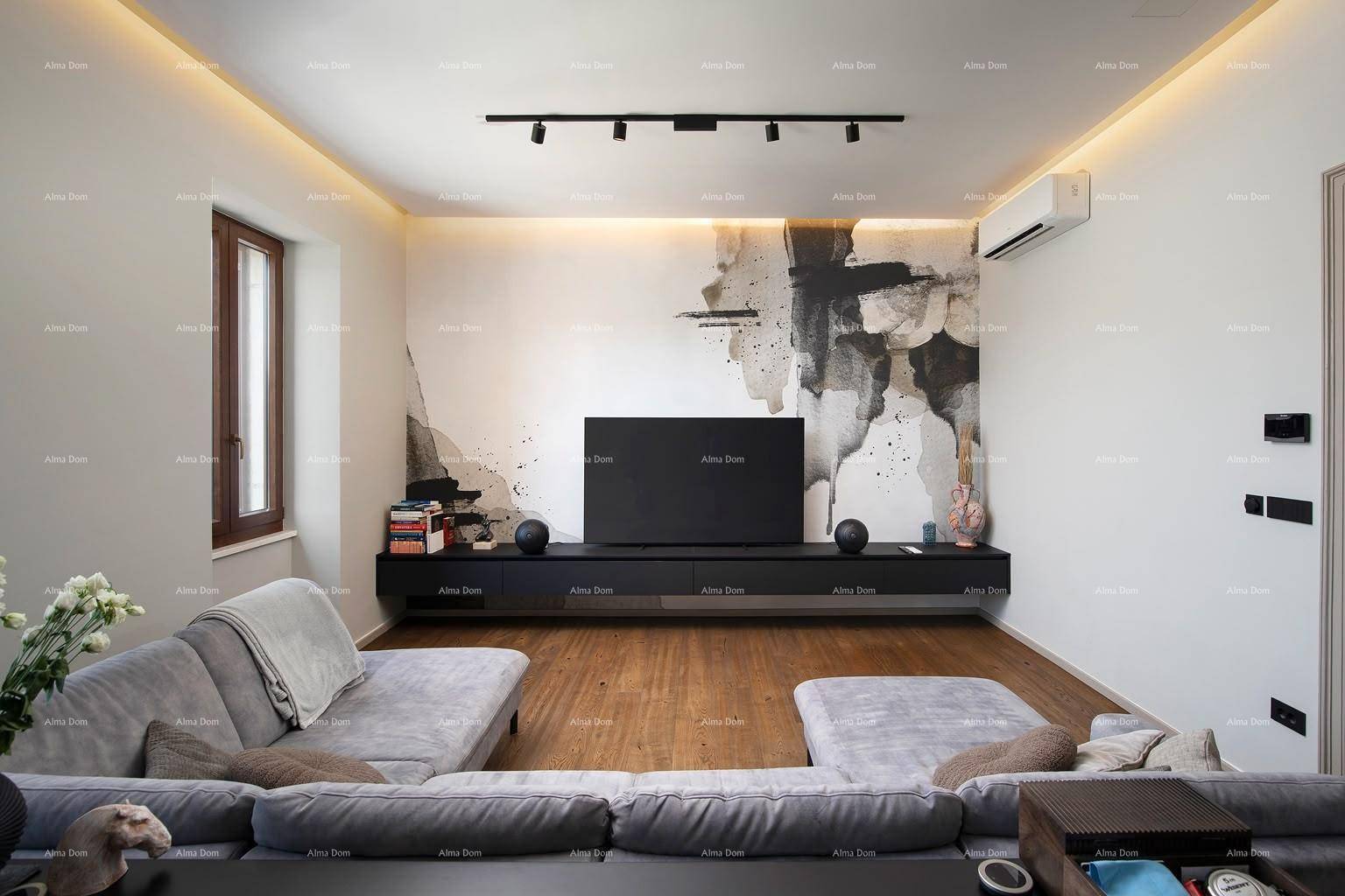 Modernes Wohnzimmer mit bequemer Couch, großem Fernseher und Klimaanlage für angenehmes Raumklima.
