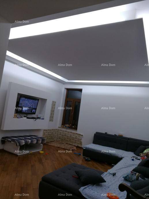 Wohnzimmer mit modernem Deckenlicht, Wandfernseher und bequemer Sitzecke.