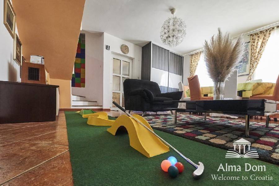 Geräumiger Wohnbereich mit Minigolfanlage, Sofa und Essbereich im Hintergrund.