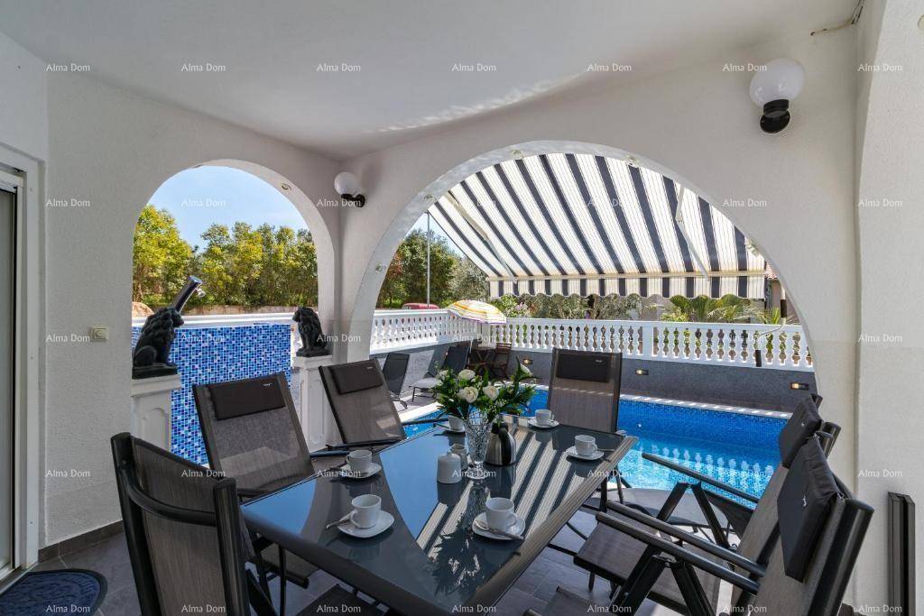 Überdachte Loggia mit Esstisch und Stühlen, ideal für Mahlzeiten im Freien mit Blick auf den Pool.