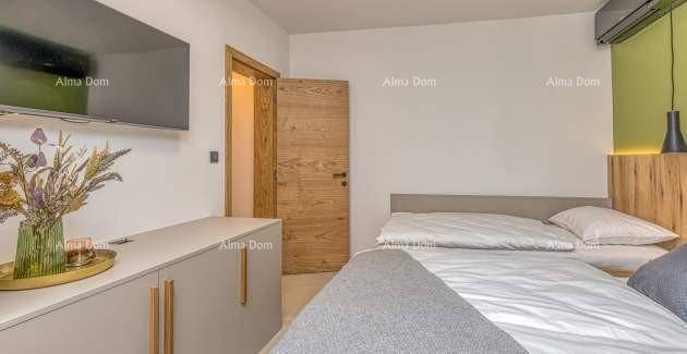 Schlafzimmer mit Doppelbett, Wandfernseher und Holztür, die zu einem anderen Raum führt.