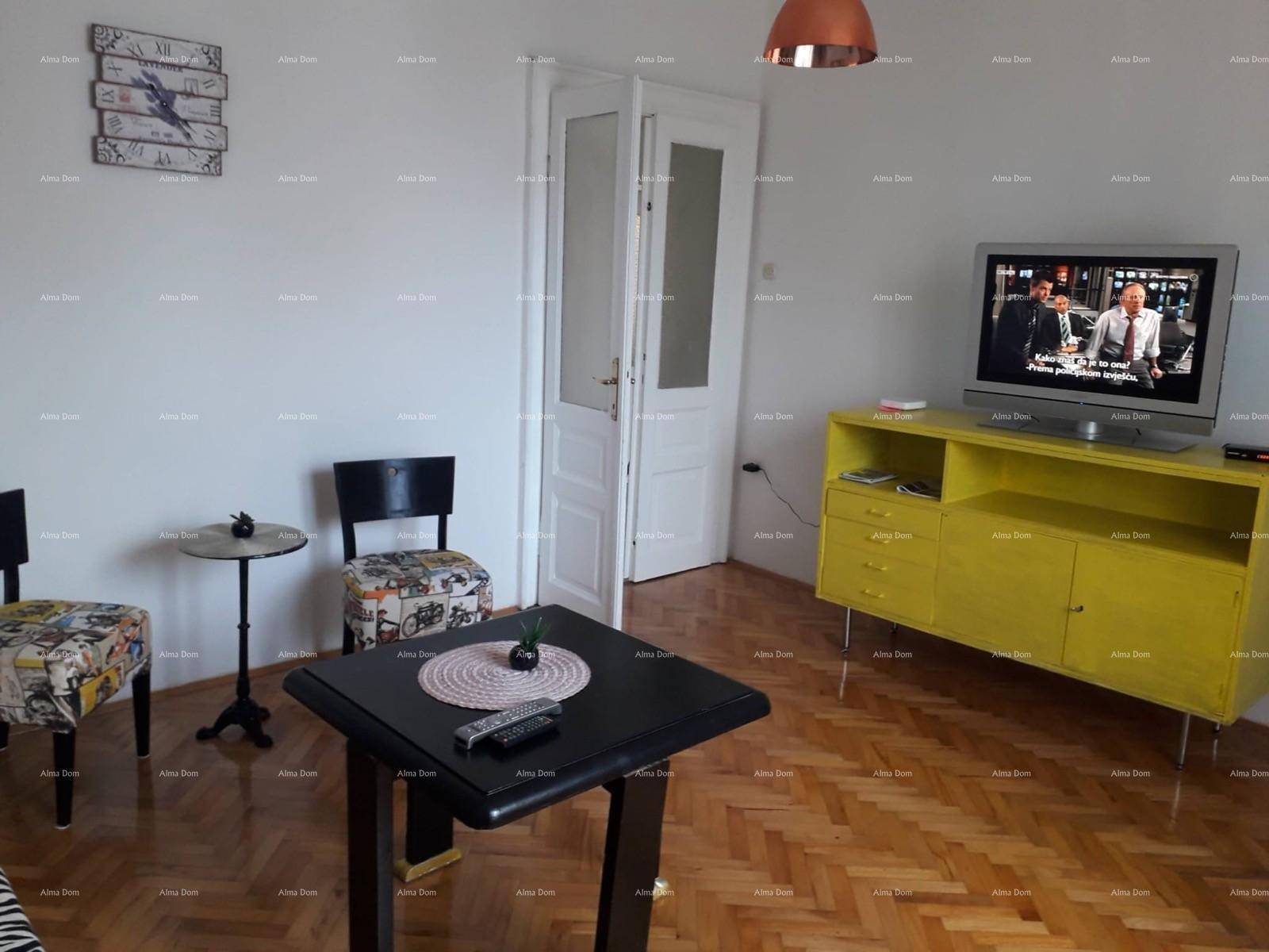 Wohnzimmer mit Fischgrätparkett, gelbem Sideboard und Fernseher für Unterhaltung und Entspannung.