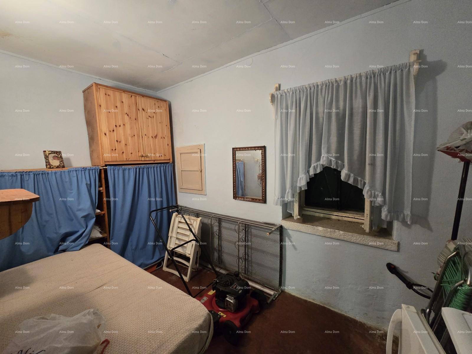 Einfaches Schlafzimmer mit hellblauen Wänden, Holzschrank und einem Fenster mit Vorhängen.